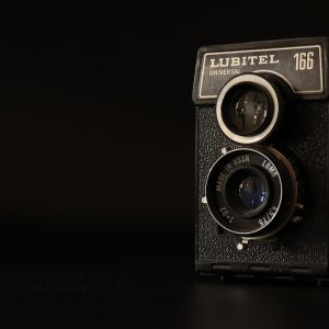 数据中心工程师戴着工牌站在机柜通道中回望镜头，蓝色指示灯在背景里连成一条光带